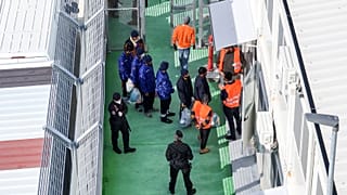 An aerial photograph taken by a drone shows migrants entering a detention center for processing following earlier court rejections, in the port of Shengjin