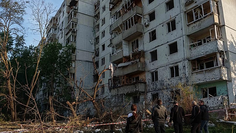 Menschen betrachten ein Wohnhaus, das nach einem russischen Angriff auf Kyjiw beschädigt wurde, 2. Juni 2026