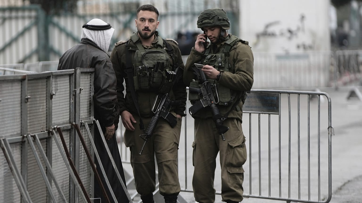 جنود إسرائيليون يدققون في هوية فلسطيني عند أحد الحواجز في بيت لحم أثناء توجهه إلى المسجد الأقصى لأداء أول صلاة جمعة من شهر رمضان، في 7 مارس 2025.