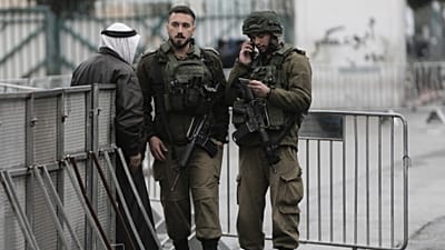 جنود إسرائيليون يدققون في هوية فلسطيني عند أحد الحواجز في بيت لحم أثناء توجهه إلى المسجد الأقصى لأداء أول صلاة جمعة من شهر رمضان، في 7 مارس 2025.