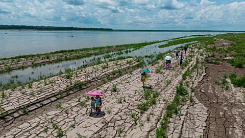 FILE - People walk through a part of the Amazon River that shows signs of drought in Santa Sofia, on the outskirts of Leticia, Colombia, Oct. 20, 2024. 