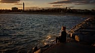 ARCHIVIO - Una donna è seduta su un frangiflutti di fronte al Mar Mediterraneo a Barcellona, Spagna, martedì 3 febbraio 2026. (Foto AP/Emilio Morenatti)