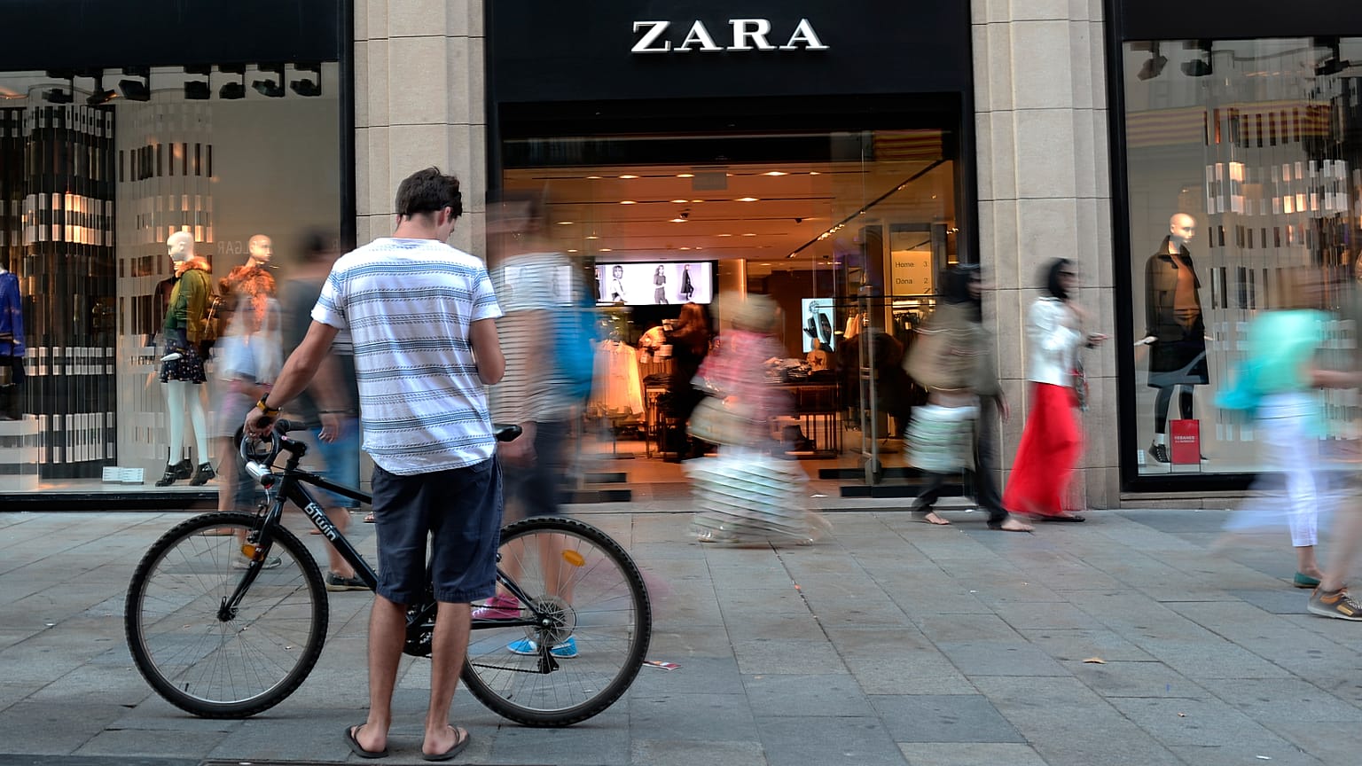 أشخاص يمرون سيراً أمام متجر "زارا" في برشلونة، إسبانيا، في أغسطس 2021.