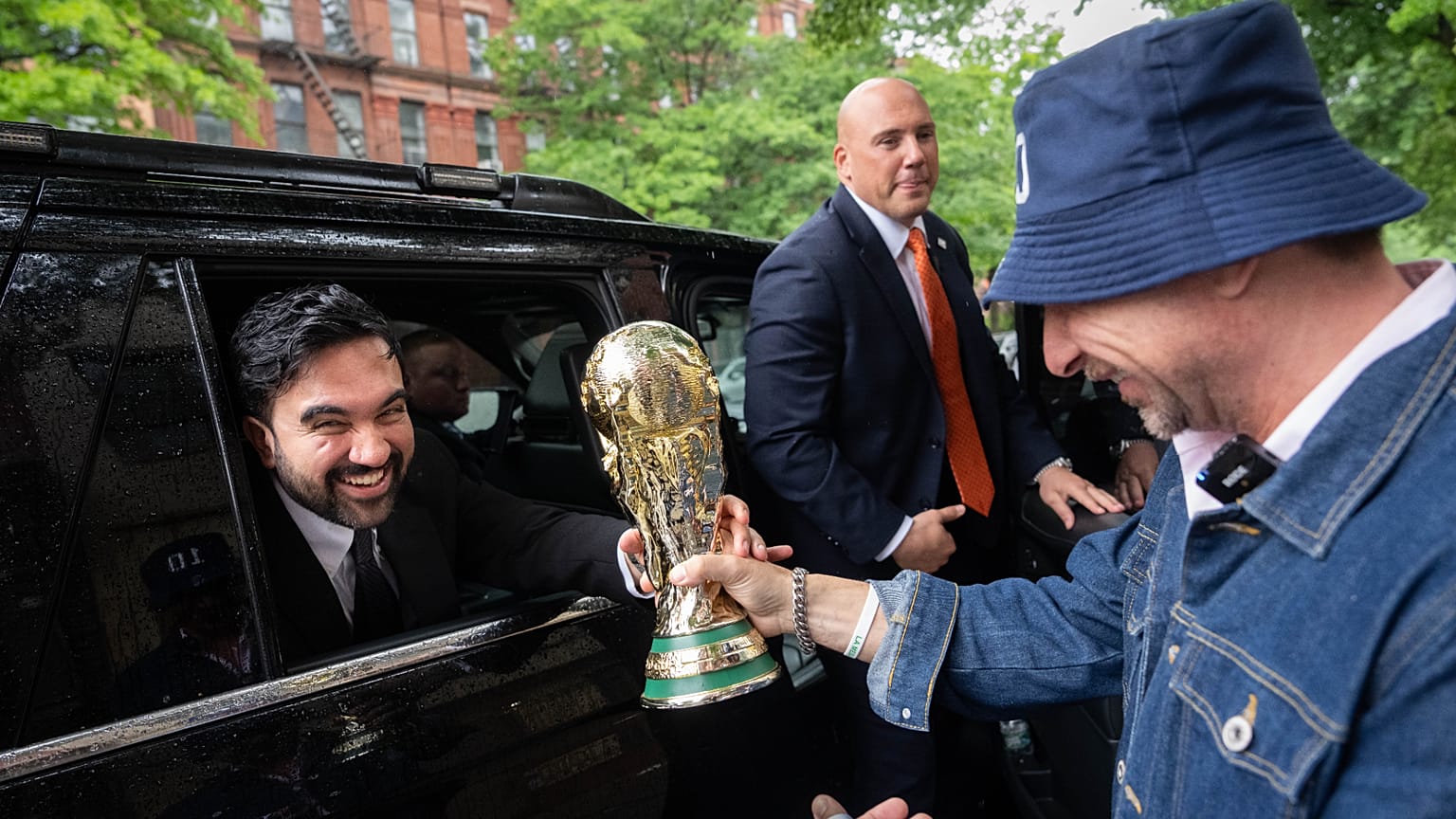 New York Mayor Zohran Mamdani is passed a replica World Cup Trophy by Ezequiel Cecchi, 49, after making a World Cup soccer tournament announcement at Harlem Tavern