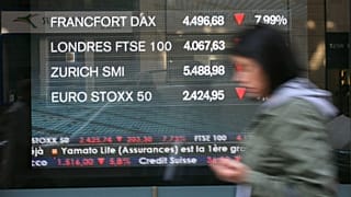 Un passant marche devant un écran diffusant des informations boursières, avec les indices des Bourses européennes, le vendredi 10 octobre 2008, dans une rue de Paris.
