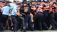 Протестующие вступают в стычку с полицейскими, перегородившими улицу, во время демонстрации в Тиране