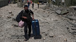 رجل يحمل أمتعته يعبر سيرا على الأقدام عبر جسر مدمر أصيب في غارة جوية إسرائيلية في القسمية بالقرب من مدينة صور الساحلية جنوب لبنان، الخميس 16 أبريل 2026. (AP Photo/محمد الزعتري