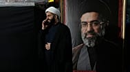 FILE: A cleric speaks on his cellphone next to a portrait of Iran's Supreme Leader Ayatollah Mojtaba Khamenei, in Tehran, 18 May 2026