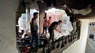 Palestiniano inspeciona e limpa os destroços após um ataque aéreo israelita