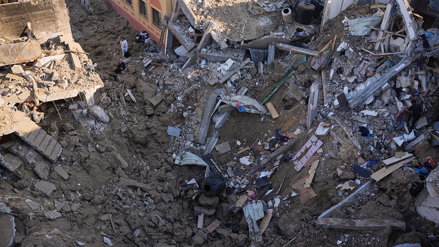 نساء فلسطينيات يتفقدن أنقاض مبنى دمر في غارة جوية إسرائيلية في دير البلح بوسط قطاع غزة، الجمعة 29 مايو 2026. (AP Photo/عبد الكريم حنا)