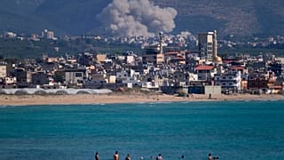 سبح الناس على شاطئ عام بينما يتصاعد الدخان، في الخلفية، من غارة جوية إسرائيلية ضربت قرية القليلة، كما شوهدت من مدينة صور الساحلية الجنوبية بلبنان، الثلاثاء 2 يونيو 2026. 