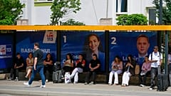 Seçim afişlerinin asılı olduğu başkent Priştine'deki bir otobüs durağında insanlar bekliyor, 5 Haziran 2026