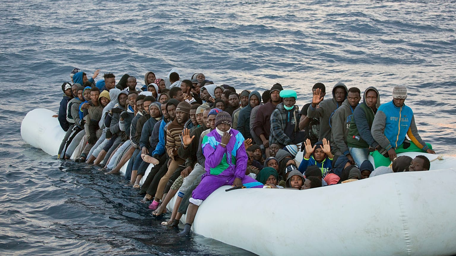 Migrants and refugees wait to be helped by members of the Spanish NGO Proactiva Open Arms, as they crowd aboard a rubber boat sailing out of control in the Mediterranean Sea a