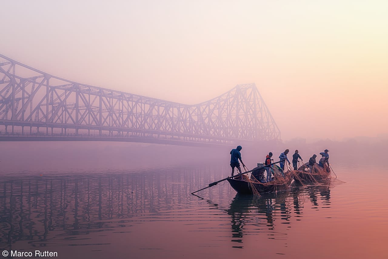 Pescadores izan sus redes al amanecer en Bengala Occidental, India
