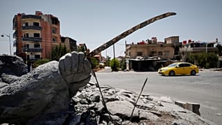 سيارة تمر بجوار تمثال مدمر في بلدة السويداء ذات الأغلبية الدرزية بسوريا، الجمعة 25 يوليو 2025