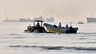 A tractor tows a small boat through shallow water as cargo ships and industrial vessels are anchored in the Strait of Hormuz off Bandar Abbas, Iran, Monday, June 1, 2026. 