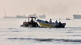 A tractor tows a small boat through shallow water as cargo ships and industrial vessels are anchored in the Strait of Hormuz off Bandar Abbas, Iran, Monday, June 1, 2026. 