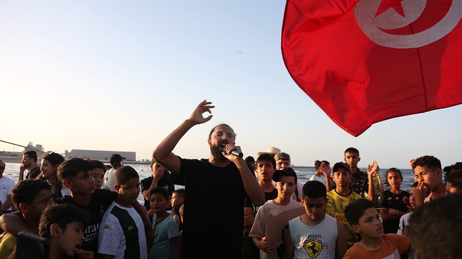 الناس يحتجون على شاطئ ملوث بالمصانع الكيميائية في قابس بتونس الجمعة 5 يونيو 2026. لافتة باللغة العربية مكتوب عليها "تفكيك المصانع". (AP Photo/باسم عويني)