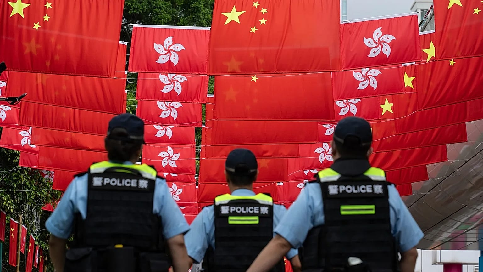 Police officers walk past the Chinese and Hong Kong flags in Hong Kong, 1 July, 2024