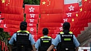 Police officers walk past the Chinese and Hong Kong flags in Hong Kong, 1 July, 2024