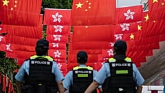 Agentes da polícia passam junto às bandeiras da China e de Hong Kong em Hong Kong, em 1 de julho de 2024