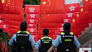 Police officers walk past the Chinese and Hong Kong flags in Hong Kong, 1 July, 2024