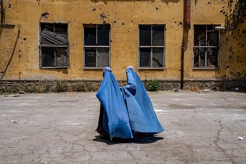 Afghan women wait to receive food rations distributed by a humanitarian aid group in Kabul, 28 May, 2023