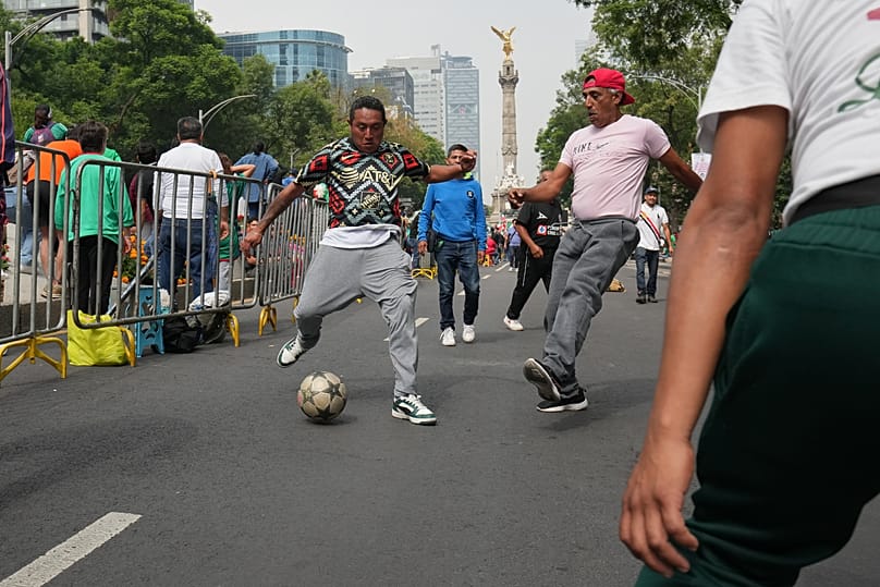 Adeptos de futebol brincam com uma bola antes de participarem numa onda mexicana ao longo da avenida Reforma, na Cidade do México, sábado, 6 de junho de 2026, antes do Campeonato do Mundo da FIFA.