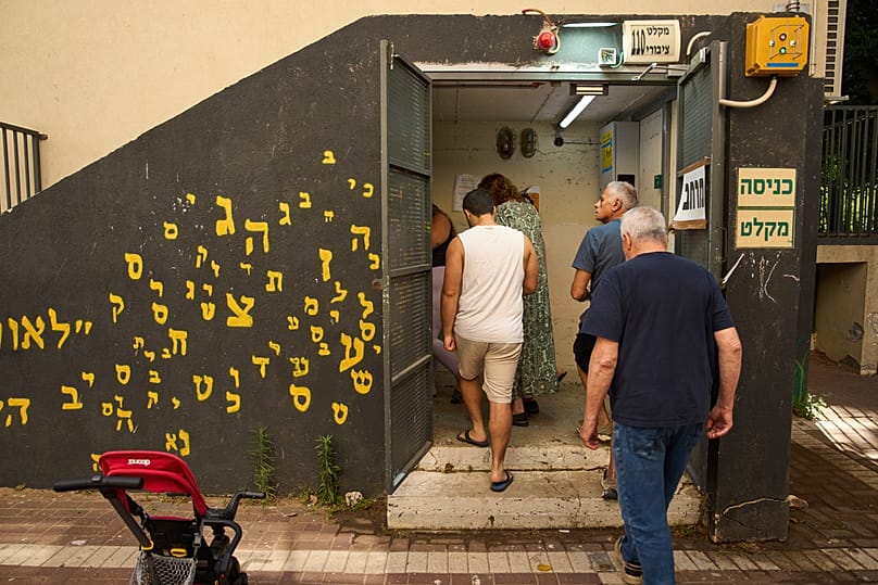 People take shelter as air raid sirens warning of incoming Iranian missiles in Ramat Gan, Israel, Monday, June 8, 2026. 