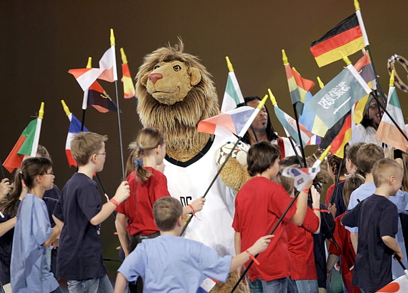 Das offizielle Maskottchen "Goleo" ist bei der Endauslosung für die Fußball-Weltmeisterschaft 2006 von Kindern umringt, die Nationalflaggen der qualifizierten Länder tragen.