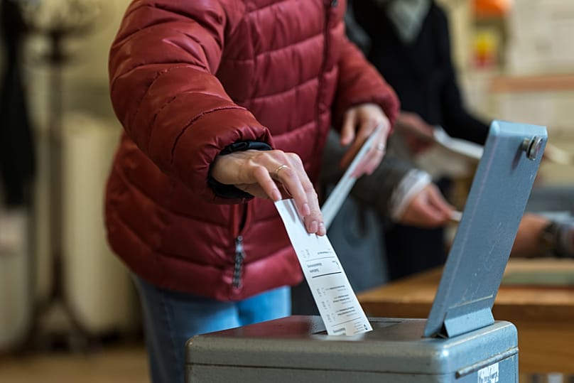 Um eleitor suíço deposita o boletim na urna num centro de voto em Berna, 30 de novembro de 2014