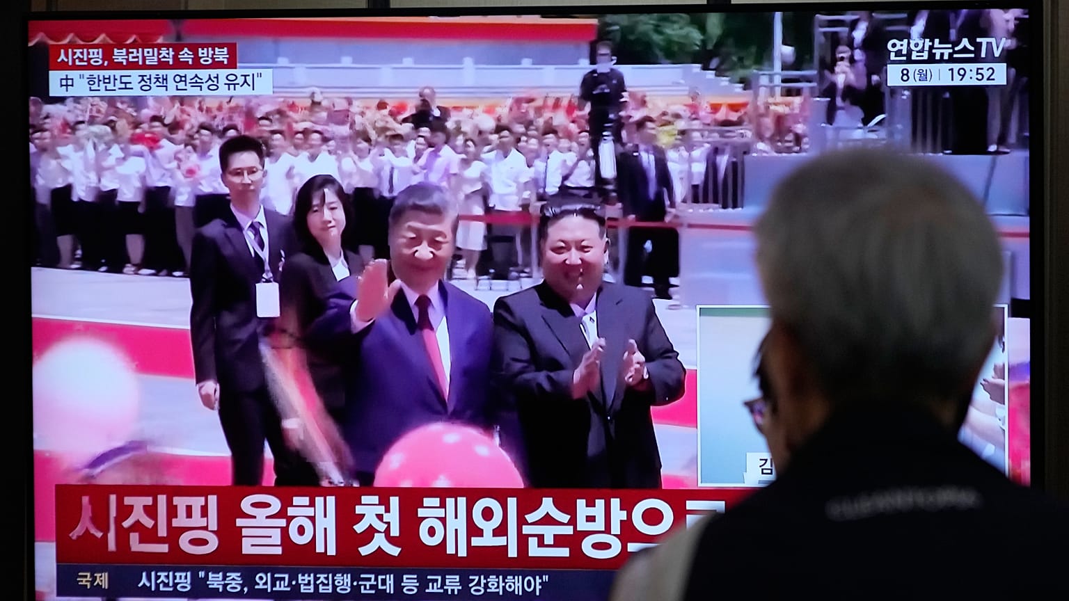 İnsanlar, Çin Devlet Başkanı Şi Cinping ile Kuzey Kore lideri Kim Jong'un gösterildiği bir televizyon ekranını izliyor.