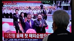 Menschen verfolgen im Fernsehen Chinas Staatschef Xi Jinping und Nordkoreas Machthaber Kim Jong.