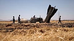 يقوم المزارعون برش المياه في حقل زراعي محترق بجوار مقذوف بالقرب من بلدة نجها بسوريا، الاثنين 8 يونيو 2026، بعد سقوط حطام إطلاق الصواريخ الإيرانية خلال الصراع الإيراني الإسرائي