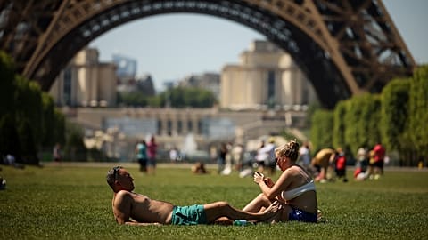 People enjoy the sun next to the Eiffel Tower in Paris, May 27, 2026. 