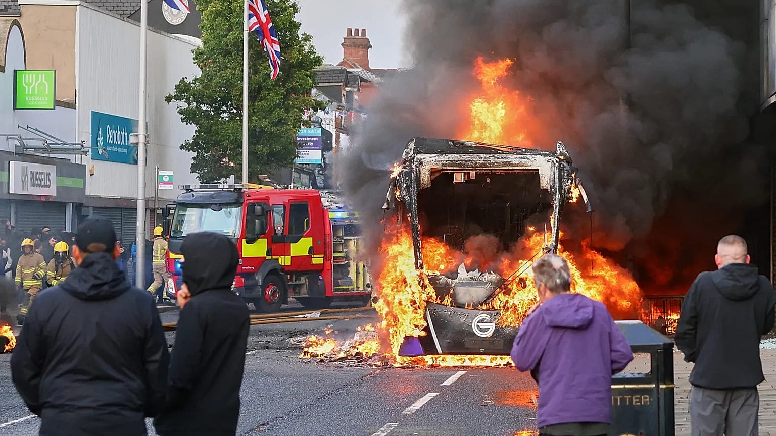 People watch as a vehicle burns during a protest in East Belfast following a stabbing incident in Belfast, Tuesday, June 9, 2026.