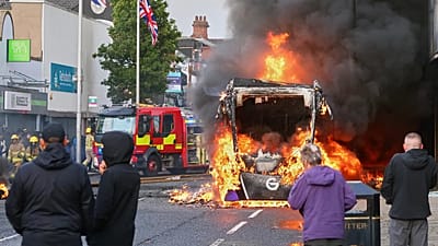 People watch as a vehicle burns during a protest in East Belfast following a stabbing incident in Belfast, Tuesday, June 9, 2026.