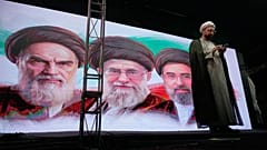 رجل دين يقف على منصة أمام صور آية الله روح الله الخميني وعلي خامنئي  ومجتبى خامنئي، طهران، 7 يونيو 2026.
