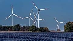 Wind turbines turn behind a solar farm in Rapshagen, Germany, Thursday, Oct. 28, 2021. 