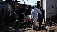 Police officers carry the body of a person on a stretcher after a mass shooting at an informal settlement near Johannesburg, 10 June, 2026
