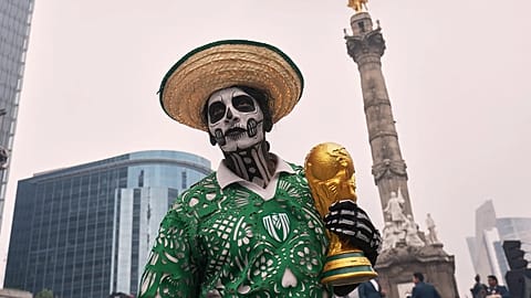 A dancer holds a replica of the World Cup trophy as soccer fans stand along Reforma Avenue in Mexico City, Saturday, 6 June 2026 ahead of the FIFA World Cup.