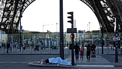 Archivo - Una persona sin hogar duerme junto a la Torre Eiffel, el miércoles diez de abril de 2024, en París.