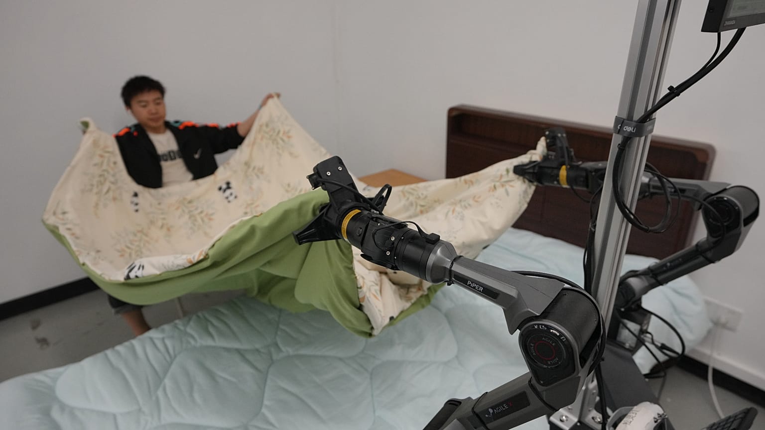 Trainer und Roboterarme falten am 29. Mai 2026 während einer Medientour in Beijing E-Town in China eine Matratze.
