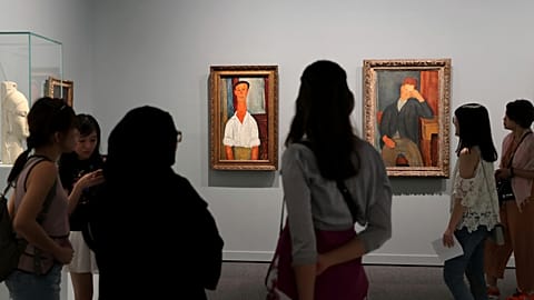 People view paintings, left to right; Gaston Modot and The Young Apprentice, both by Amedeo Modigliani, on display as a part of the Rendez-vous à Paris exhibition