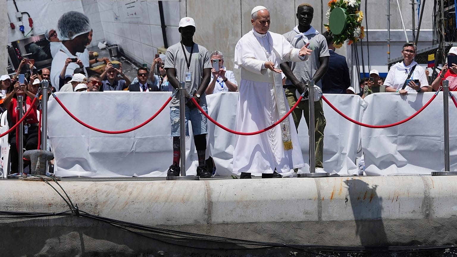 Pope Leo XIV throws a bouquet of flowers into the sea, flanked by migrants, during a meeting with organisations working with migrants in Arguineguin at the Canary Islands.