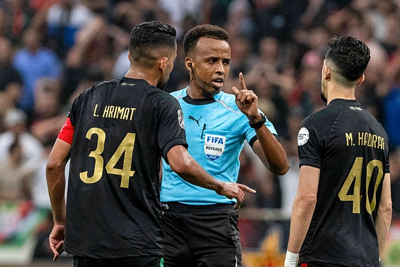 Referee Omar Artan, center, of Somalia, is confronted by players after calling a penalty kick during the CAF Champions League final soccer match.