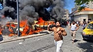  People run in front of burned cars that were attacked in an Israeli airstrike in the southern port city of Sidon, Lebanon, Wednesday, June 10, 2026.
