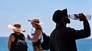 Ένας τουρίστας πίνει νερό από μπουκάλι στην παραλία της Βαρκελώνης