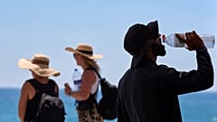 ARCHIVO - Un turista bebe agua en un día caluroso en la playa de Barcelona, ​​España, 2 de julio de 2025.