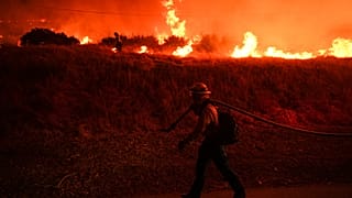 FILE - A firefighter monitors flames caused by the Hughes Fire along Castaic Lake in Castaic, Calif., Jan. 22, 2025. 